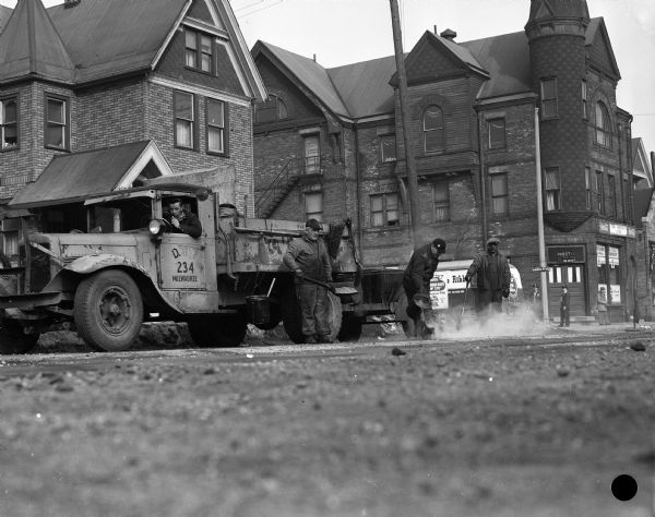 Milwaukee streets department employees repair the intersection of Meinecke Avenue and 12th Street.  Behind them, a Blatz truck is making a delivery to the Wisconsin Hall Tavern.