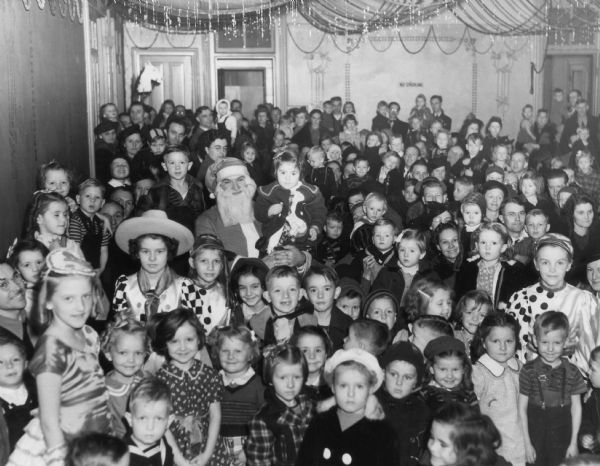 Santa Claus surrounded by children at a Christmas Party sponsored by the United Automobile Workers Local 121 of Janesville.