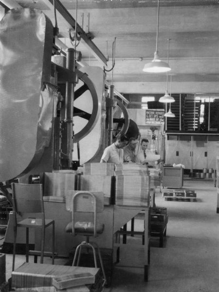 Punch press equipment at one of the Wisconsin prisons used for the manufacture of license plates and traffic signs. This photograph appeared in a 1961 publication of the Division of Corrections entitled "Rebuilding People" within a section about the Corrections Industries Section. The work depicted is described as both a service to the state and training for the inmate.
