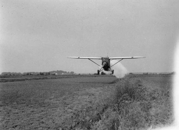 Airplane owned by the Agricultural Dusting Service of Ft. Lauderdale, Florida, dusting a cranberry marsh in Wood County for leaf hoppers. The photographer is identified only as "NFT".