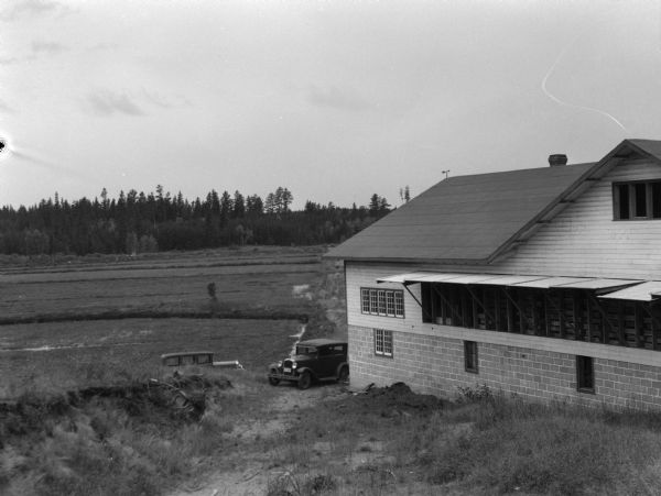 View of a cranberry marsh and warehouse. In the foreground is a warehouse for the storage of harvested cranberries.