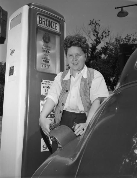 A woman pumping gas at the H.W. Risberg & Sons Black Eagle Service Station, 1200 East Washington Avenue.