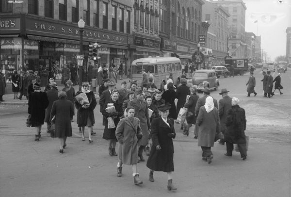 Christmas shoppers crossing the street at the corner of King Street on the Capitol Square in front of Kresge's, 25-27 East Main Street.