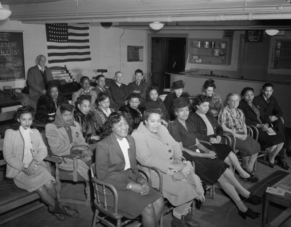 Group of 15 women and six men attending a meeting at USO Service Club.  The group is predominantly African Americans. Probably taken in First Unitarian Society Parish Hall, 15 E. Dayton Street.