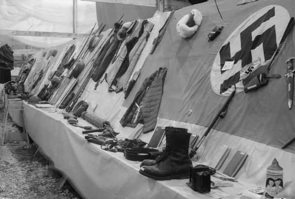 Display of German "war junk," including fire arms, clothing and a German Nazi flag, at the East Side Business Men's Festival.  The souvenirs displayed were collected by 80 servicemen.