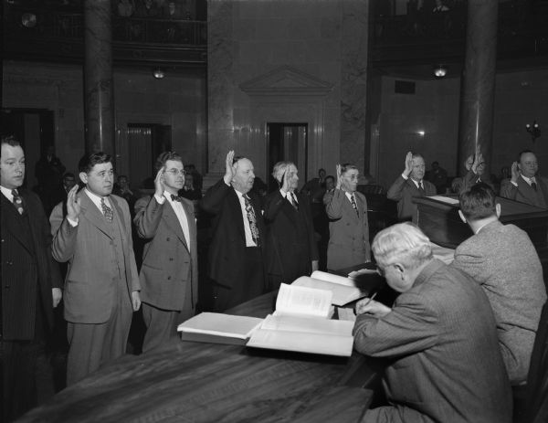 Swearing-in ceremony of 6 of 17 new Wisconsin State Senators.  Left to right: Henry W. Meier (D-Milwaukee), Arthur A. Lenroot (R-Superior), Frank E. Panzer (R-Oakfield), Robert P. Robinson (R-Beloit), Melvin J. Olson (R-South Wayne), and William A. Draheim (D-Neenah).  Lieut. Gov. George M. Smith administered the oath in the Wisconsin State Capitol.