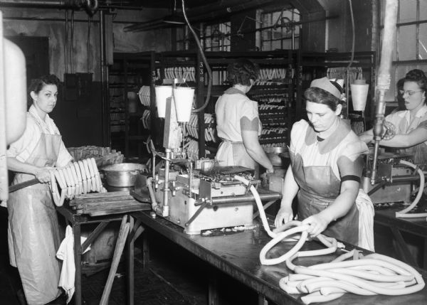 Four women operating sausage-making equipment at the Oscar Mayer Company during World War II.