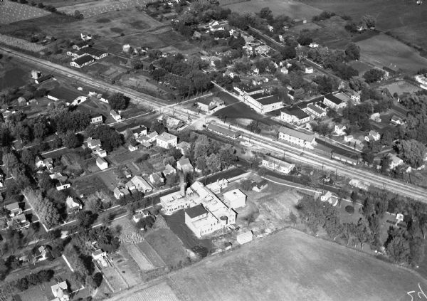 Aerial view of the town, including business, houses, and railroad tracks cutting through the town.