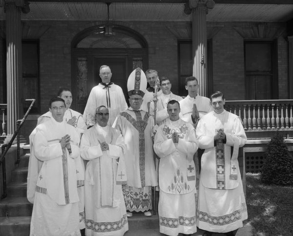 Seven new Catholic priests and two existing Madison priests posing with Bishop William P. O'Connor at St. Raphael Cathedral. The new priests include the Reverends Archie Adams, Raymond Dunn, John T. Flanagan, Bernard J. Pickarts, Michael F. Stein, and Thomas Vickerman. The existing priests include the Right Reverend Monsignor Edward Kinnney, rector of St. Rapheal Cathedral, and Right Reverend Jerome Hastrich, Madison vicar-general and chancellor of the Madison Diocese.