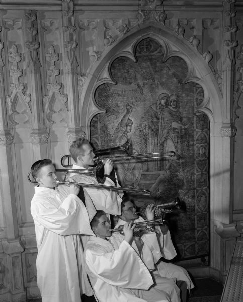 A quartet of horn players, first row David Lewis and William Howard, back row Robert Reuter and Jim Christensen, play for Easter services at Luther Memorial Church in front of a stained glass window.