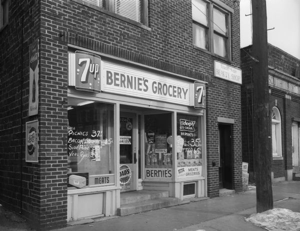 Exterior of Bernie's Grocery store located at 334 West Lakeside Street, and a portion of the South Side Bank. The store was operated by Bernard J. Holtman.