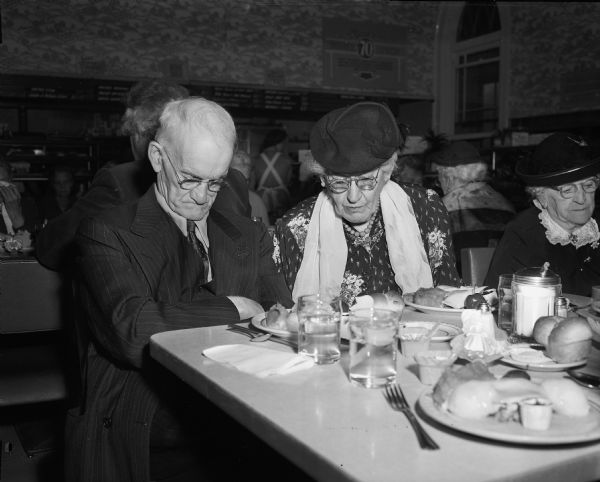 William Thorp and Hattie Reed bow their heads in prayer before Thanksgiving dinner is served by the Volunteers of America to 56 members of its Sunset Club.