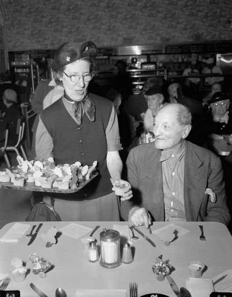 Bessie Koen serves the first course of the traditional turkey-and-trimmings dinner to James Eckert. Dinner was served by the Volunteers of America to 56 members of its Sunset Club.