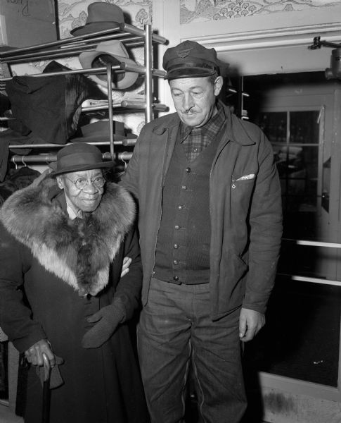 Mary Hawkins, assisted by Thorwald Anderson, Checker Cab driver, arrives for a Thanksgiving dinner served by the Volunteers of America to 56 members of its Sunset Club.