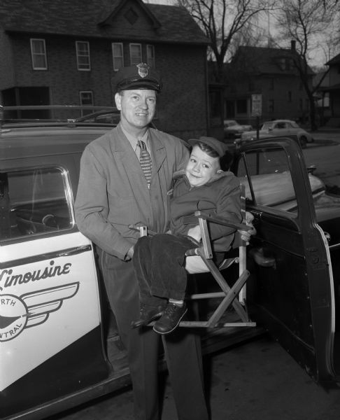 David Lindl, Easter Seal boy, being carried to taxicab by driver, Mr. Coster.