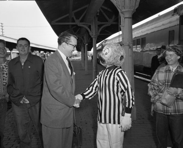 Walt Kelly, famous cartoonist, shaking hands with a person dressed as Pogo, one of his cartoon characters.