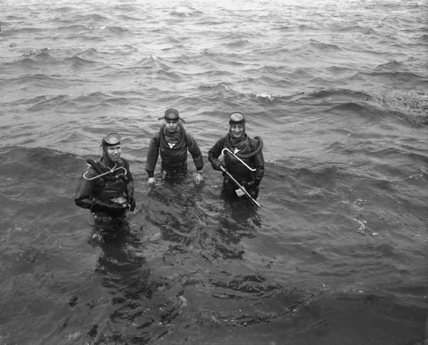 Madison Diving Club members Harold Stitgen, president, Reverend Herbert Schaak, treasurer, and James Filer dressed for scuba diving in Lake Mendota off Conklin Park.