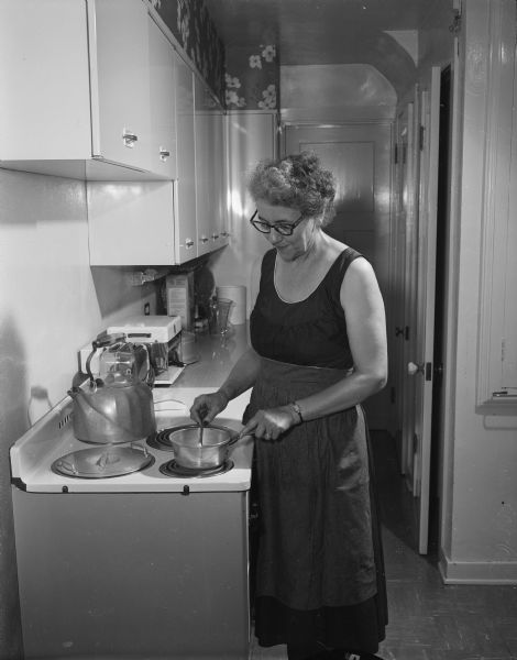 Glenn M. Wise (Mrs. John Wise), Wisconsin's first woman Secretary of State, posing in the kitchen cooking.