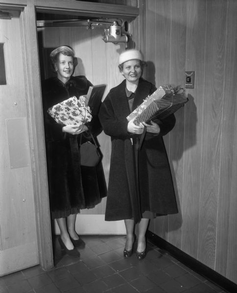 Betty Westby and Mildred Loshek, members of the East Side Women's Club, bring gifts for the Morningside Sanatorium in Madison and the Skaalen Home in Stoughton to the club's Christmas party at the East Side Business Men's clubhouse.
