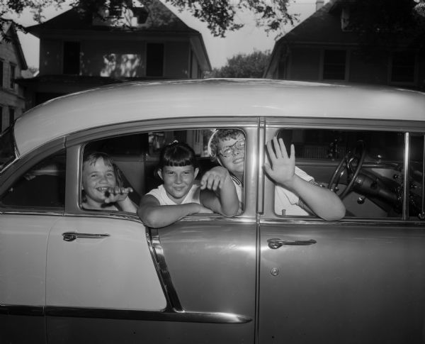 Three hearing impaired children leaving in a car for "The Retreat," a summer camp near Wautoma, Wisconsin. The trip is sponsored by the Parents Council for the Deaf at Lapham School and Hear Incorporated.