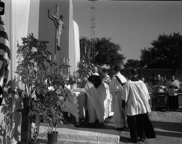 The Confraternity of Christian Doctrine pontifical field mass held at Breese Stevens Field. The Most Reverend John Treacy, bishop of the La Crosse Diocese and celebrant of the pontifical mass, standing at the altar with other clergy.