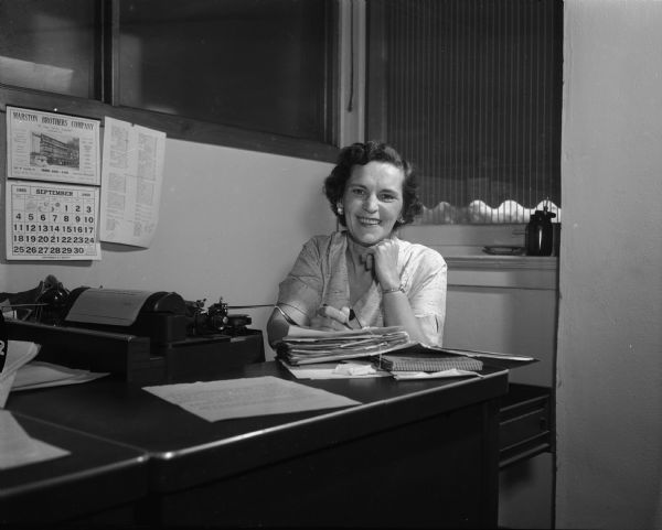 Bertha Elbel Rupp, assistant society editor, seated behind her desk at the "Wisconsin State Journal."