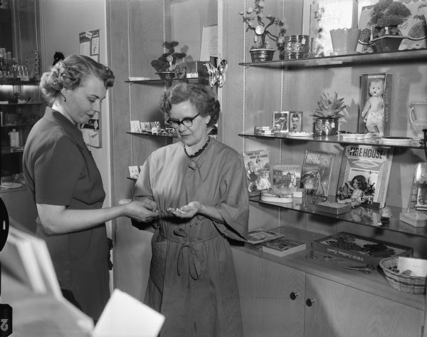 Mrs. Garth Heisig, Arlington Heights, Illinois, purchases a silver bracelet in the Madison General Hospital Gift shop from Mrs. S.W. Sherlock, a hospital auxiliary member and gift shop volunteer.