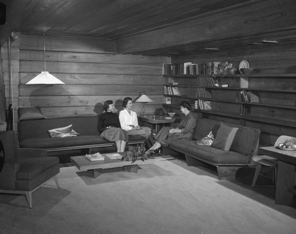 Ruth Pew (Mrs. J.C.), Frances Hurst (Mrs. William), president of the Madison League of Women Voters, and Katharine Becker (Mrs. Robert M.), member of the board of directors of the League, sitting in the living room of the Pew House designed by architect Frank Lloyd Wright. The home, located at 3650 Lake Mendota Drive, was featured on the second annual house tour of the League of Women Voters in cooperation with the Madison Chapter of the Wisconsin Division of Architects.
