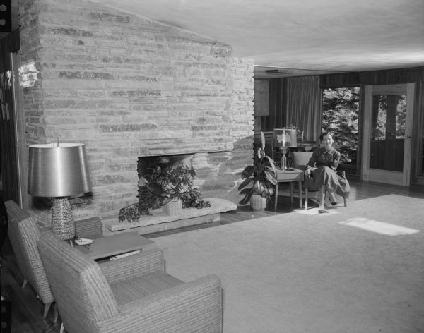 Annrita Lardy sitting in the living room of her and her husband Dr. Henry A. Lardy's new house, designed by Herb Fritz, 1829 Thorstrand Road. Fritz was a student of Frank Lloyd Wright.