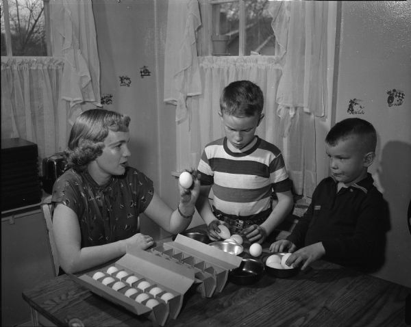 Truax Field Officers' Wives Club president, Irene Crouch, 213 North Street, and her sons, Keith, 6, and Kenneth, 10, preparing to dye eggs for the Easter egg hunt.