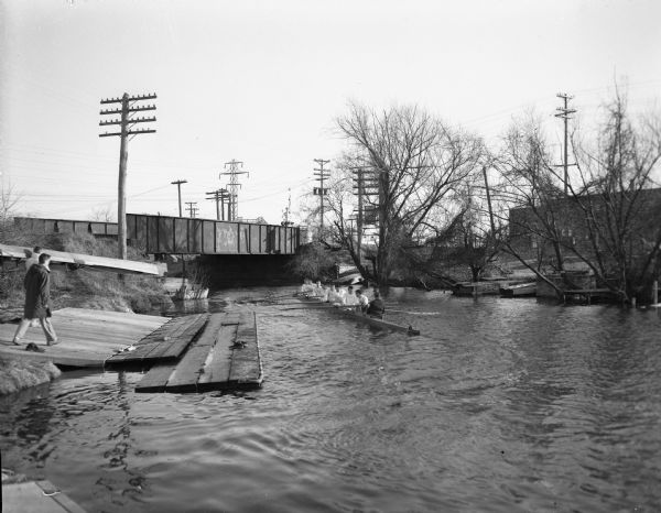 University of Wisconsin crew rowing down the Yahara River. View looking south toward railroad bridge in the 100 block of North Thornton Avenue.