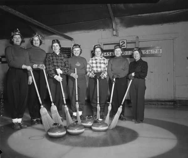 Members of the Madison Toories, the women's auxilliary of the Madison Curling Club, pose with their brooms and stones. Left to right: Frances Sanford, Charline Larson, Clare Manzer, Agnes Gurney, Marian Cottrell, Esther Onstad, and Ida Doerfer.