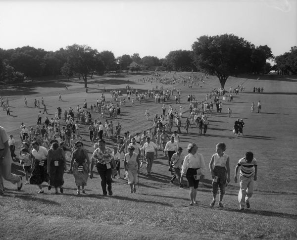 Spectators walk across Maple Bluff Golf Course during the Women's Western Golf Association Tournament.