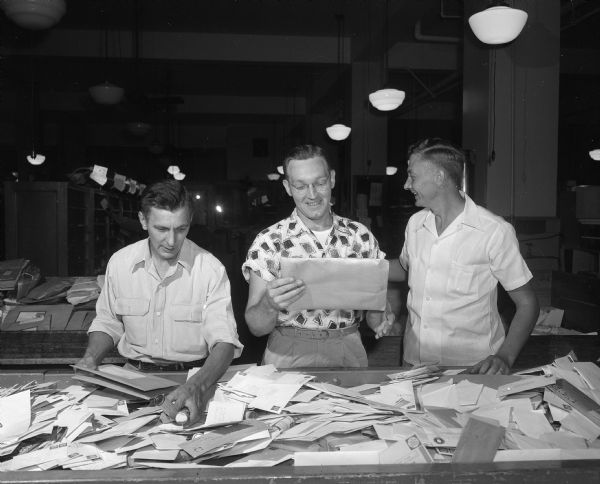 Postal clerks Stanley A. Kolenda, William G. Spencer, and Nathan C. Hillmer sorting mail at the Madison Post Office.