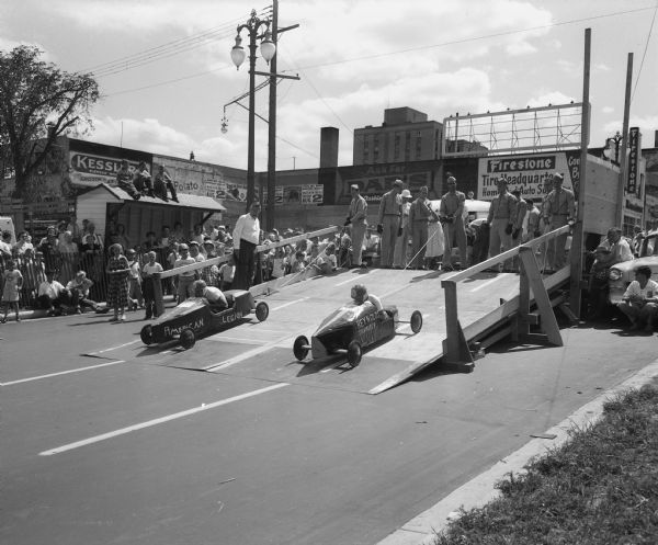 The Soap Box Derby held on East Washington Avenue leading from the Wisconsin State Capitol. Shown are two boys in their racers on the starting ramp. Starter, Genn (Pat) Holmes, is in the white shirt. Ken Zamzow of Portage is on the left, and Mike Maciag, 2741 Coolidge Avenue, is on the right.