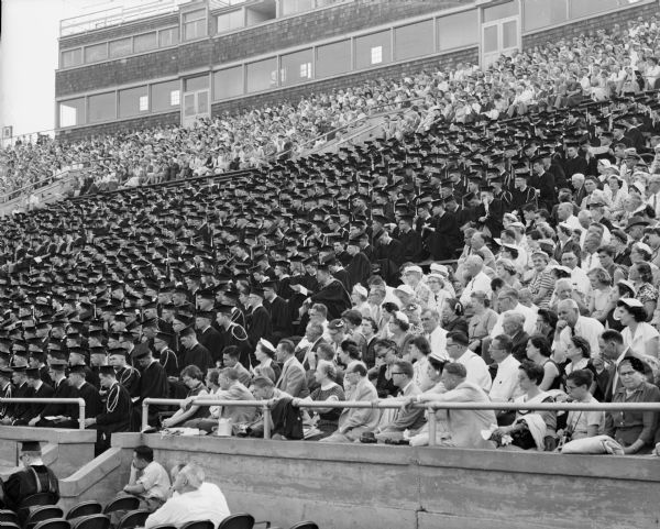 Flanked by families and friends, the University of Wisconsin class of 1955 is seated in the stands at their graduation in Camp Randall Stadium.