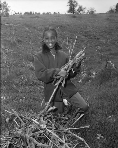 Girl Scout Phyllis Sanders of Madison gathering firewood for cooking lunch during a one day Roundup of the Girl Scouts, Brownies, and Intermediates of Districts II and IV of the Blackhawk Council of Girl Scouts on the Henry Raemisch Hereford and Trout Farm near Dodgeville. Phyllis suffered from sickle-cell anemia as a child, and her childhood friend Betty Pace was motivated by seeing Phyllis’ suffering to begin her revolutionary research into treating—and hopefully curing—sickle-cell anemia.