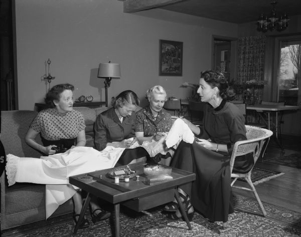 Attic Angels Association "sewing bee," where members make aprons, curtains, and other articles for the Visiting Nurse Service. Left to right: Daisy Breyer, Jane Harper, Rea Ragatz, and Mrs. John Ernest Roe, sewing chairman.