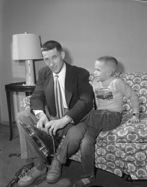 Fireman Bill Carow, member of the 1955 United States Olympic Ice Speed Skating Team, lacing his son's, Michael Carow, skates.