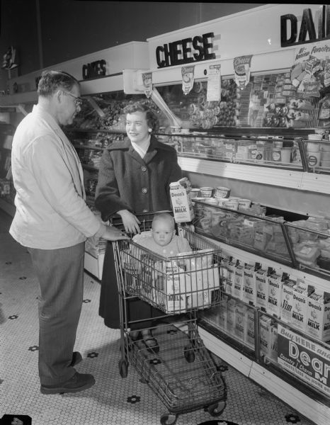 Betty Hall and her 9 month old son, Wayne, purchasing Dean's milk from Harry Gerson in the Cardinal Super Market, 120 North Fairchild Street.