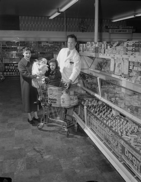 Ilena Fierker and her children, Bobby and Dicky, buying Dean's Milk from Clarence O. Furset, manager of Piggly Wiggly Food Center, 2701 University Avenue.