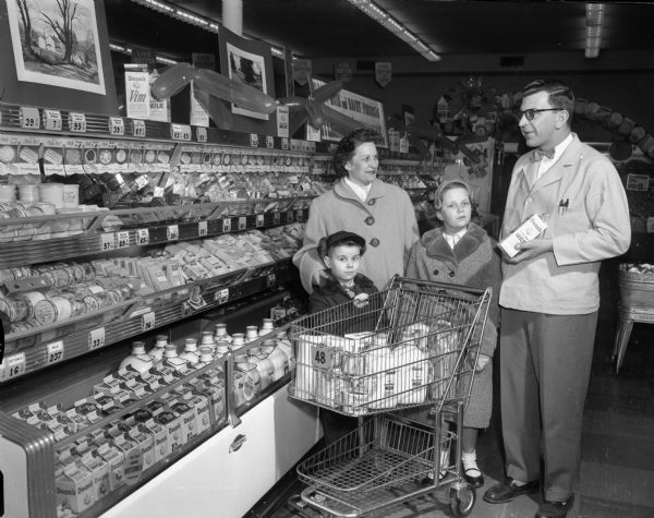 A grocery store employee helps a mother and two children purchase Dean's milk.