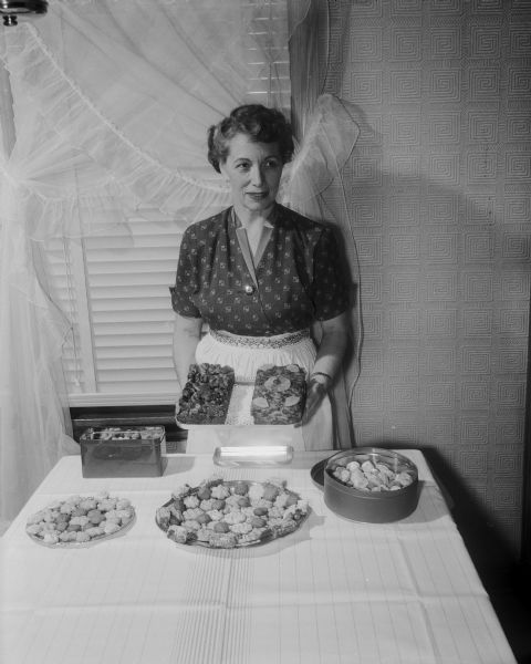 Iola Kreamer, 306 East Sunset Court, Shorewood Hills, displaying a sample of her Christmas baking, including cookies, candies, and fruit cakes.