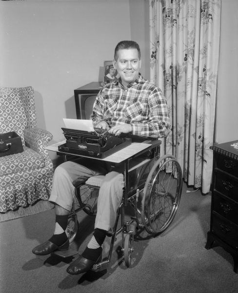 Robert Jensen typing while sitting in a wheelchair. He was paralyzed by spinal polio after serving in the United States Army in Korea.