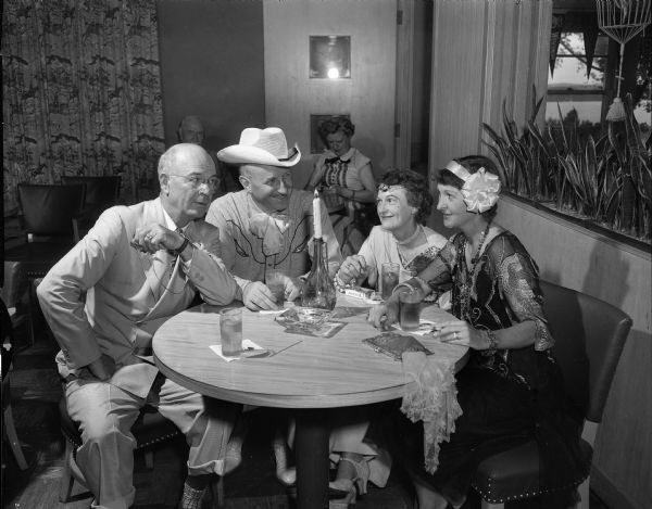 Seated at a candlelit table are, left to right: Russell Sheaf, Dr. George H. Benson, Mrs. Sheaf, and Mrs. Benson in costume at the Blackhawk Country Club 1920s costume party.