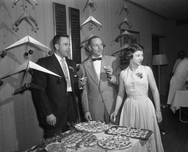 A woman and two men at the refreshment table at the Blackhawk Country Club Christmas party.