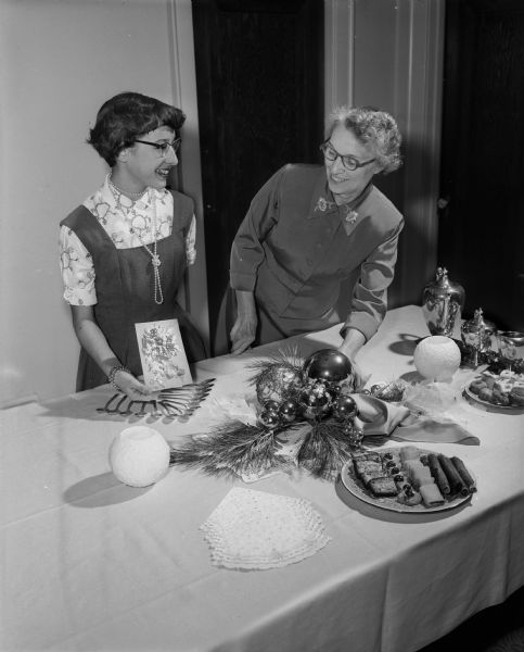 Mrs. Philip Falk with daughter Carol, displaying their Christmas table centerpiece made by Mrs. Falk which was inspired by the family Christmas card.