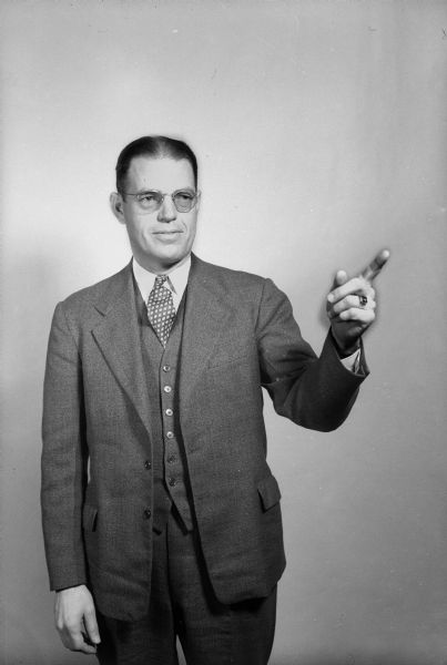 Portrait of Maurice Klinke (?), who is in a suit standing and pointing.