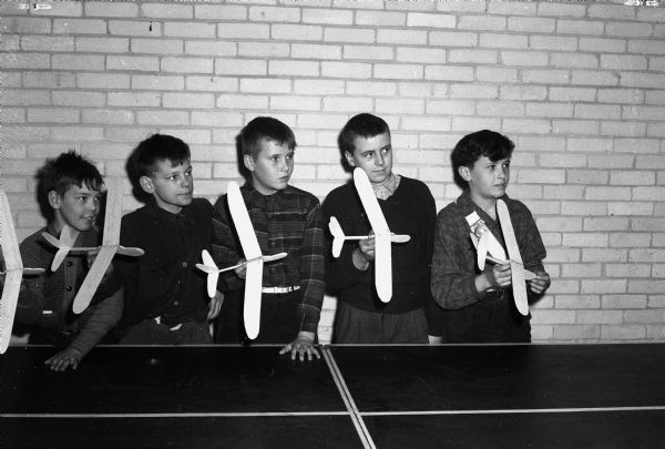 Children of parents who work at war plants participate in after school recreation program at Marquette School. Shown standing behind a ping-pong table, with the model airplanes they built are: Earl Friis, Keith McKay, Arlen Ward, Lee Rogers and Harold Smith. It was thought to be the first attempt to supply after school recreation for students in the city.