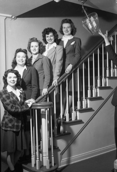 University of Wisconsin home economics students and members of the Court of Honor for the Queen of the 25th Little International Show.
Left to right: Phyllis Mann, Waukesha; Margaret "Peg" Gunderson, 2926 Hillcrest Avenue; Jane Davies, Wild Rose; Willa Rousey, Alma Center; and Margaret Biddick, Livingston. A person on the right (out of frame) is holding a light fixture out of the way of the group portrait.